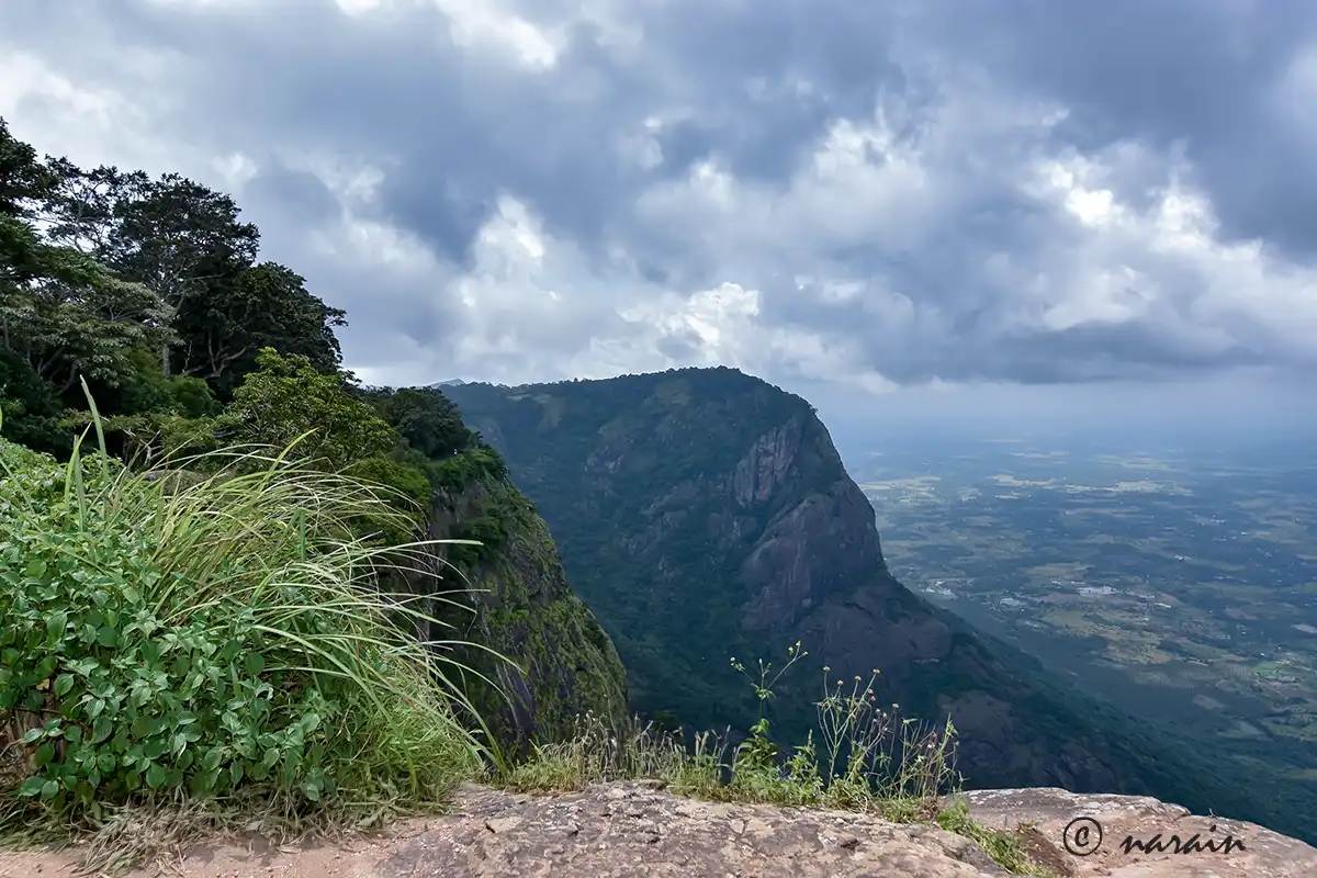 “Panoramic view of Nelliampathy hills under a bright blue sky, with distant village settlements visible from the mountaintop.”